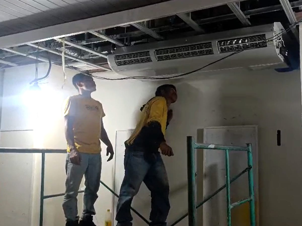 Two Lance technicians working below a ceiling-mounted indoor unit during a building fit-out